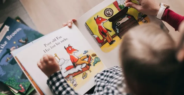 Child reading a book with an adult