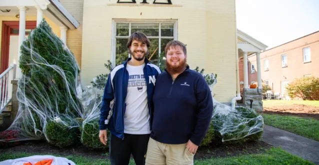 Two male students in front of Delta Tau Delta house