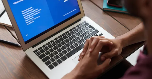 Open laptop with hands folded on the keyboard