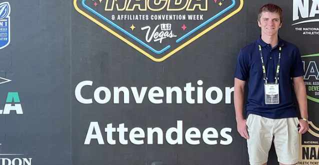 Josh Mudgett standing in front of the NACDA sign