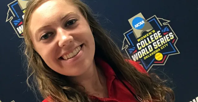 Micaela Bradley posing in front of Women's College World Series banner