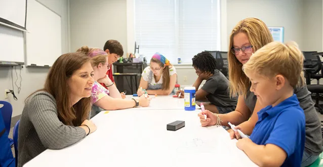 Faculty and students working with young kids in classroom