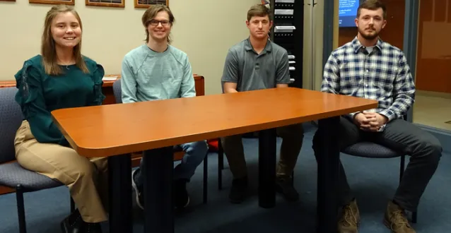 Four students sitting behind a table