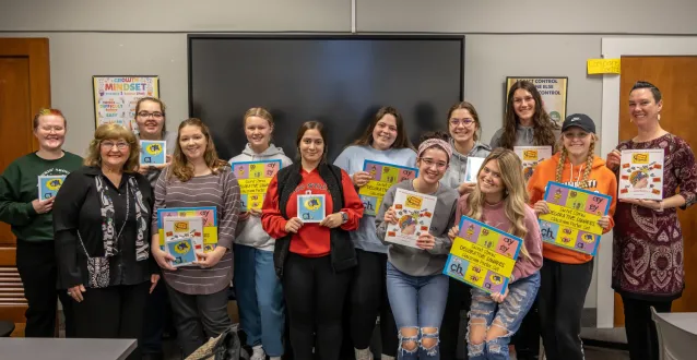 Students holding up the book