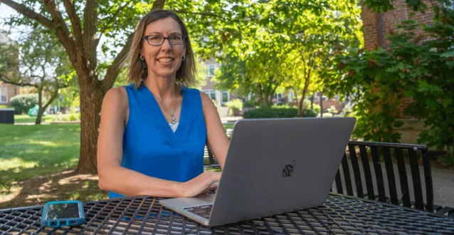 Nicole Livengood sitting outside with a laptop