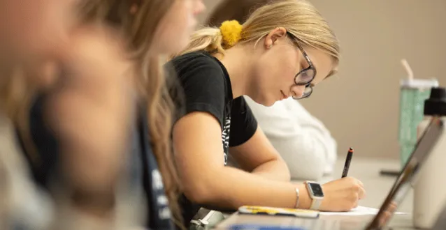 Female student writing at a desk