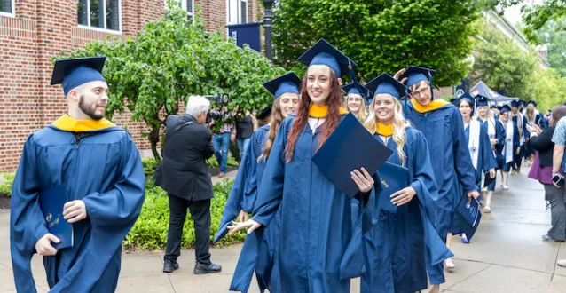 Marietta College graduates smiling during procession following Commencement.