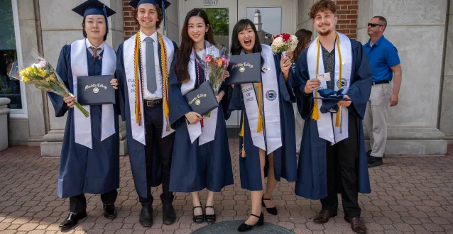 Graduates from 2025 stand proudly with their diplomas