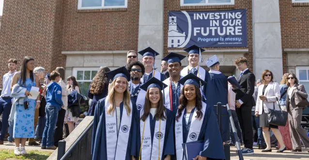 Marietta College graduates stand together happily in front of Legacy Library.