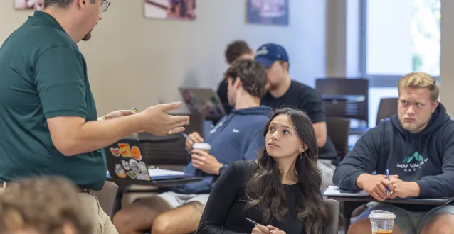 Professor Doug Ankrom speaks with a student in a lecture hall