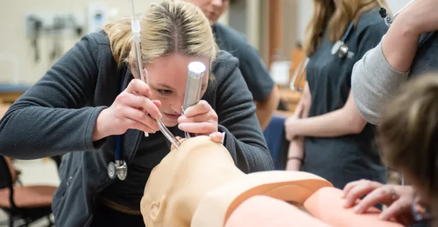 Female student learning to intubate a person