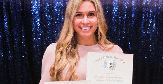 Alpha Xi Delta President Loren Coontz holds up some awards the sorority recently received.