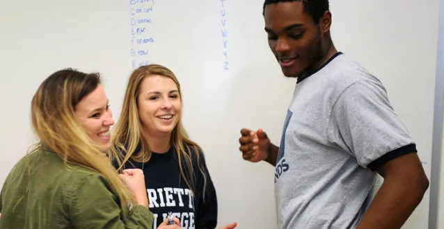 Three entrepreneur students working on a problem at the erase board