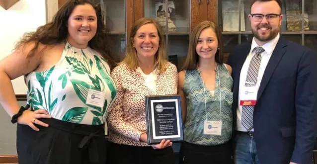 Students and faculty holding an award