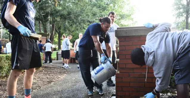 football players scrubbing the Fourth Street gateway