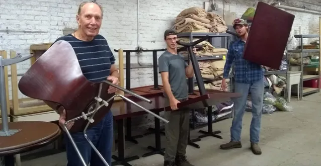 Three men carrying chairs and tables