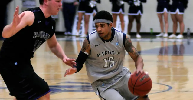 Tyler Hammond dribbles the basketball around a Mount Union defender during his Marietta College playing career