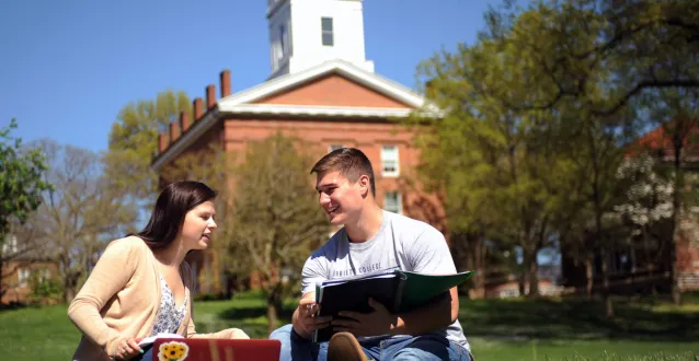 Female and male student sitting in the grass at DU Field