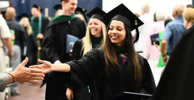 Female student shakes hands after graduating