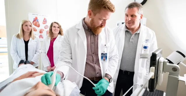 A PA professor working with students on an ultrasound procedure