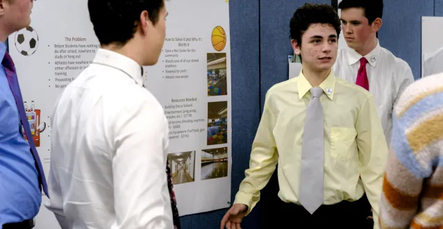 Male high school student wearing ties and dress shirts making a presentation