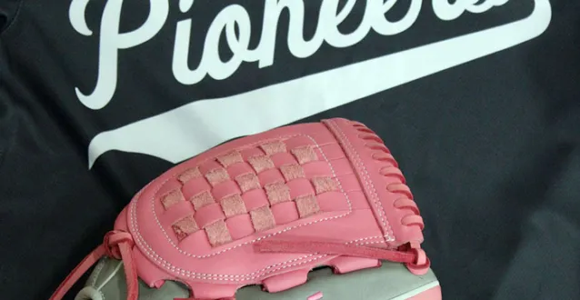 Pink softball glove on top of a softball jersey