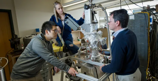 Dr. Dennis Kuhl working with 2 students in physics lab
