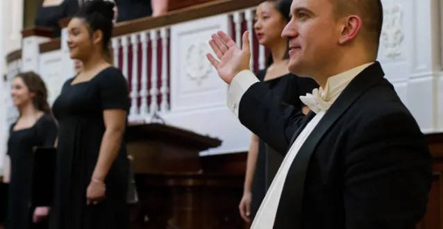 Choral director acknowledging the women's choir after singing