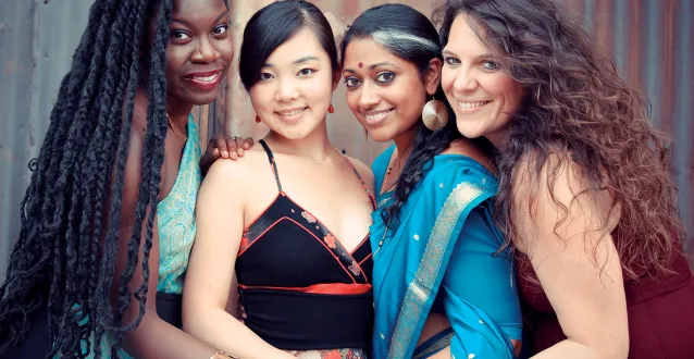 Four women huddled together holding hands