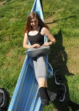 A Marietta College student studying outdoors in a hammock