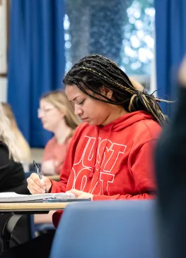 A Biology major takes notes during class