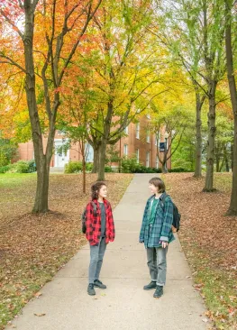 Two students chatting on a campus sidewalk.