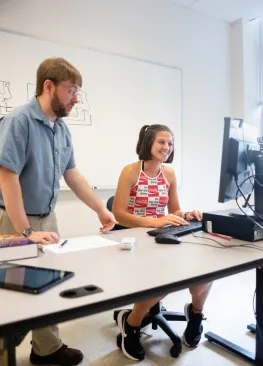 A Computer Science major works at a computer with Professor Matt Williamson