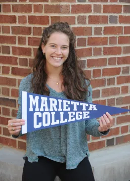 A Marietta College student holding a Marietta College pennant