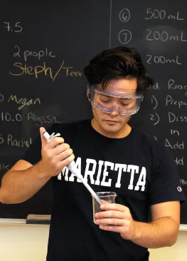 A student majoring in health science at Marietta College uses a dropper to transfer liquid into a beaker