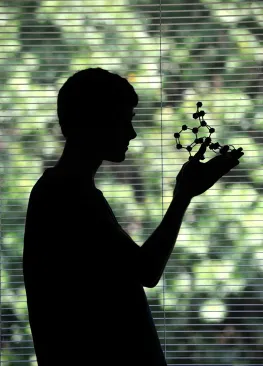 A silhouette of a student holding a model in a science lab