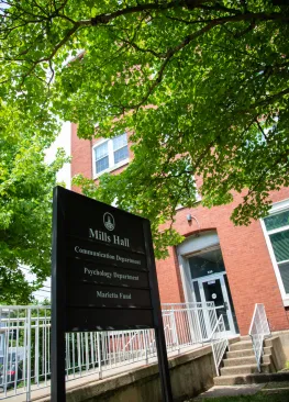 Exterior shot of Mills Hall with sign TEXT: Mills Hall Communication Department Psychology Department Marietta Fund