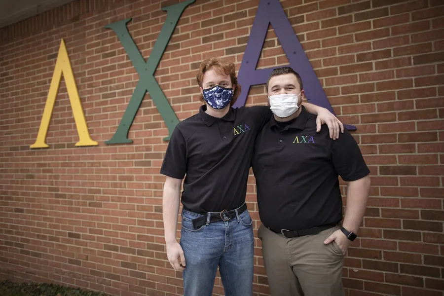 Two Marietta College students stand in front of the Lambda Chi Alpha Sign