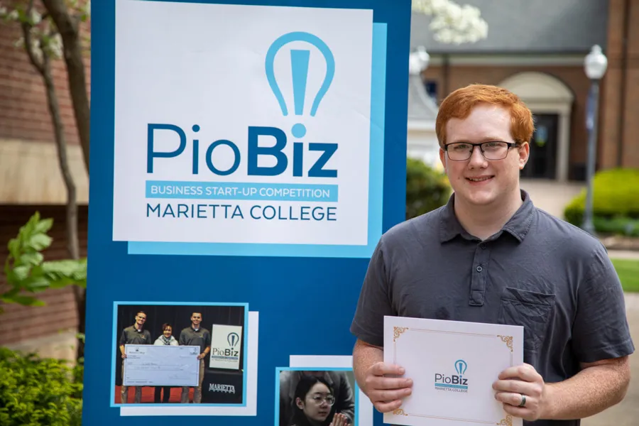 Austin McCleary holding a certificate in front of a poster board