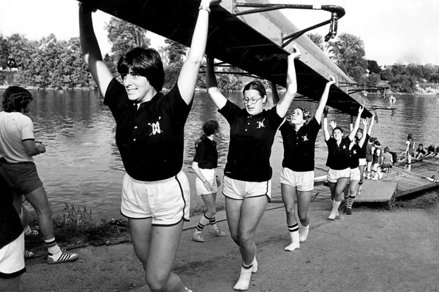 Black and white photo of the Marietta College women's rowing team carrying up their shell from the docks in 1970s